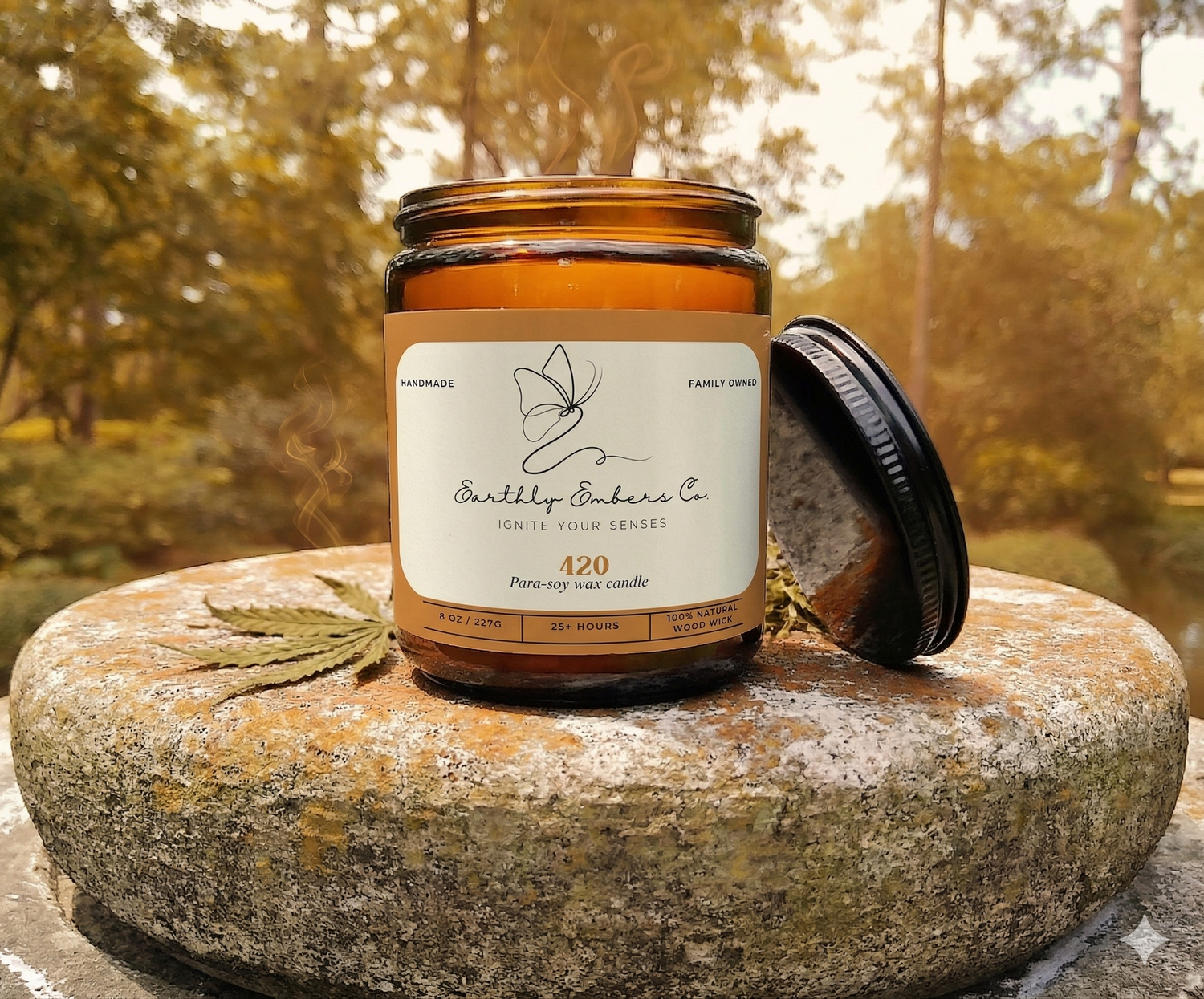 Handcrafted 420 artisan wax blend candle by Earthly Embers Co. in a signature amber glass jar with a lit wooden wick, featuring falling leaves and atmospheric smoke in a serene forest setting.