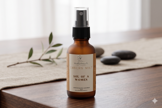 A 1oz frosted amber bottle of Earthly Embers Co. Embers Mist concentrated car spray in the scent Sol of a Women, featuring a black spray nozzle and clear cap on a wooden table.